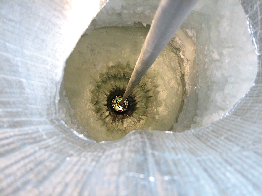 A DOM being lowered into a hole in the ice. The holes contain melted water from the hot water drill that produced the holes, but the holes will fill with ice again over time. Even if there is an issue with one of the DOMs, they can never be removed from the ice. 